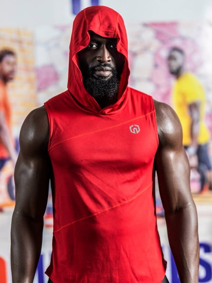 Portrait de Younousse Ba, fondateur de Home Fitness, en débardeur à capuche rouge